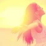 A woman with her arms outstretched in the sunlight.