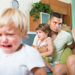 A man and two children sitting on the couch.