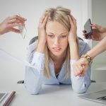 A woman sitting at the table with her hands on her head.